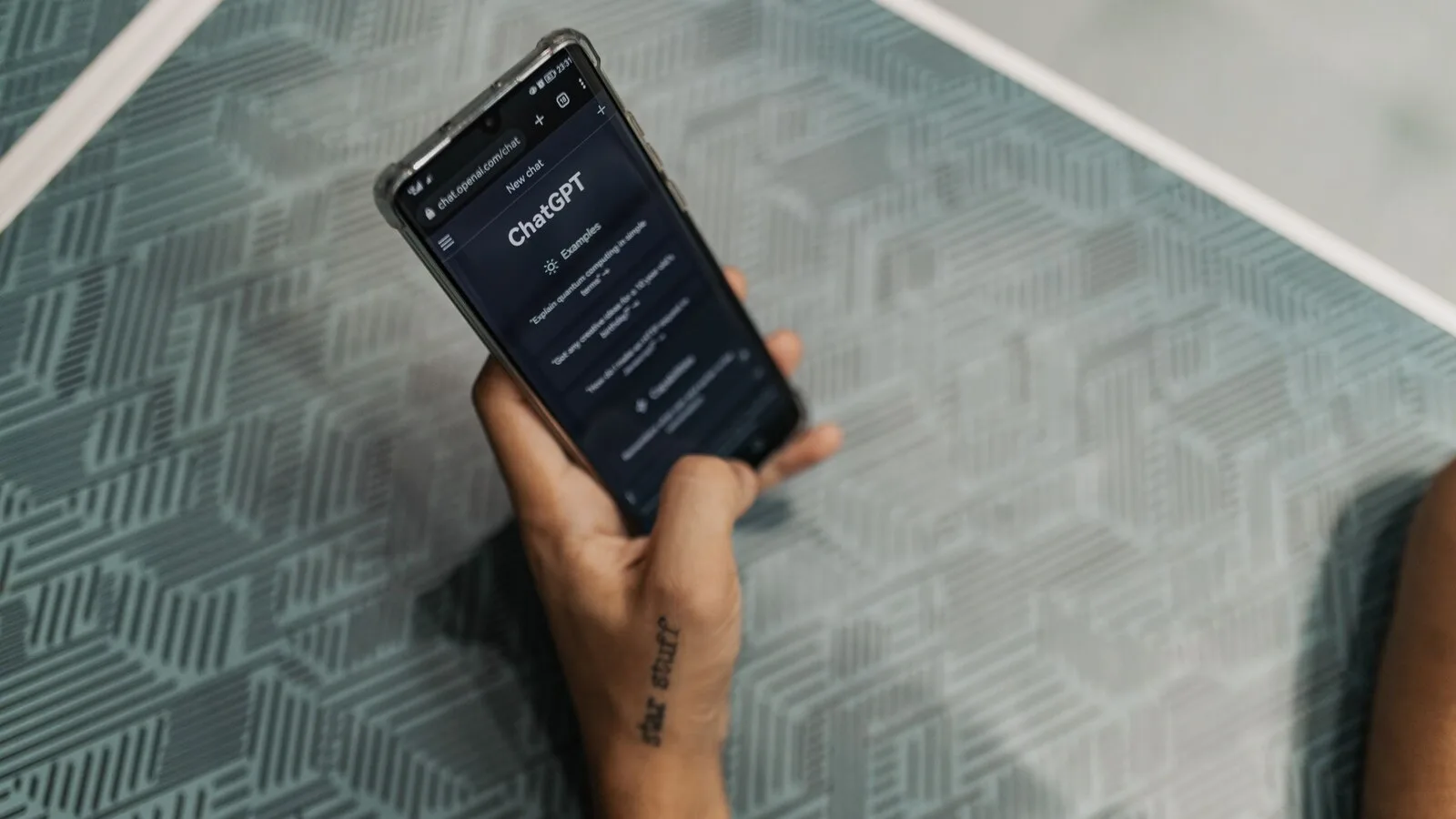 Mão a segurar um telemóvel com a app do ChatGPT aberta