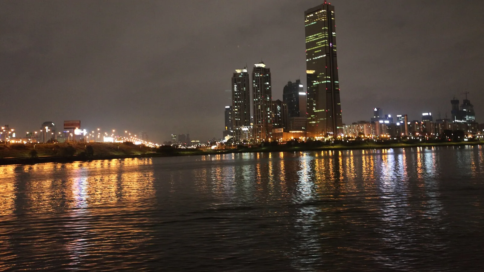 Arranha-céus iluminados do bairro de Yeouido, em Seul, à noite, refletidos no rio Han