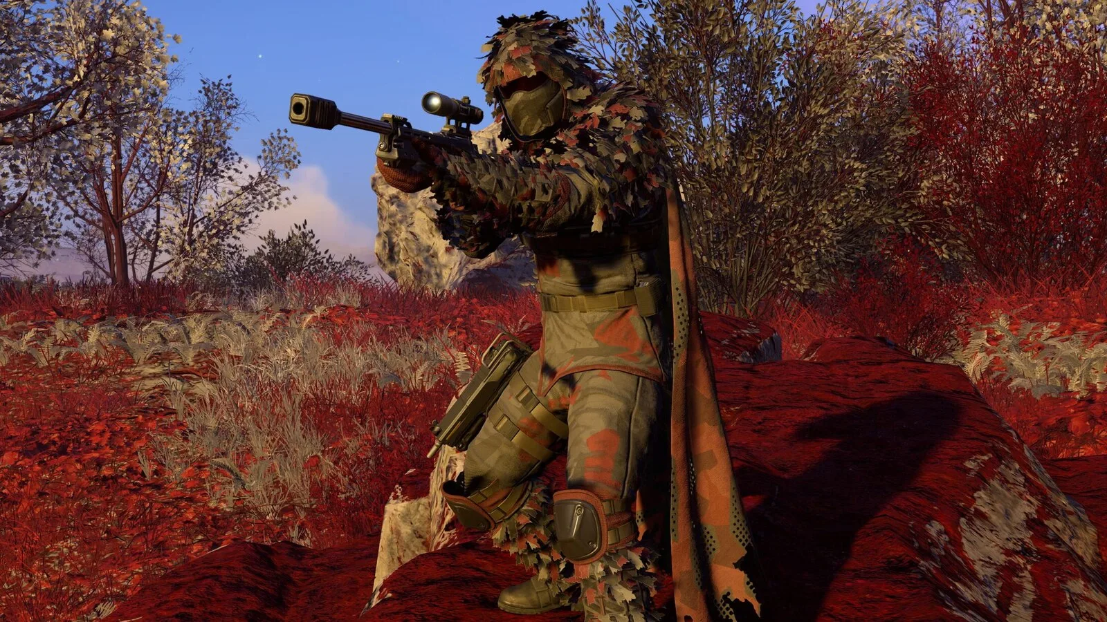 Soldado de Helldivers 2 com fato de camuflagem coberto de folhas, a apontar uma espingarda de precisão num cenário de vegetação vermelha