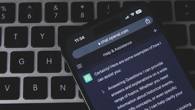 Telemóvel pousado num teclado de computador escuro, com o ChatGPT aberto no browser a mostrar uma resposta em inglês