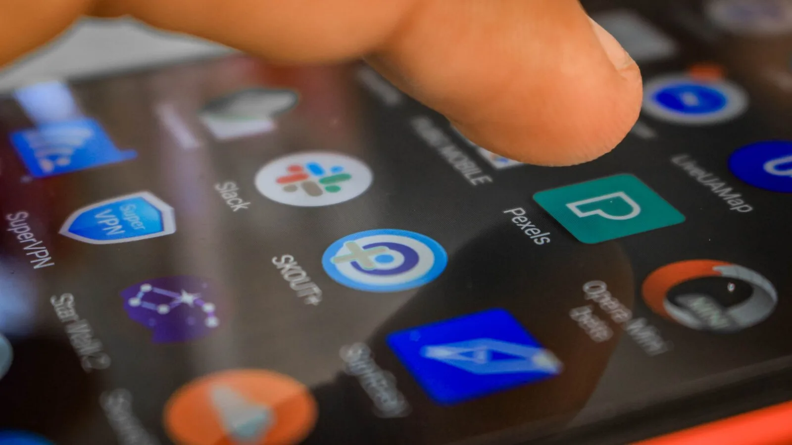 Dedo a tocar no ecrã de um telemóvel Android com vários ícones de aplicações
