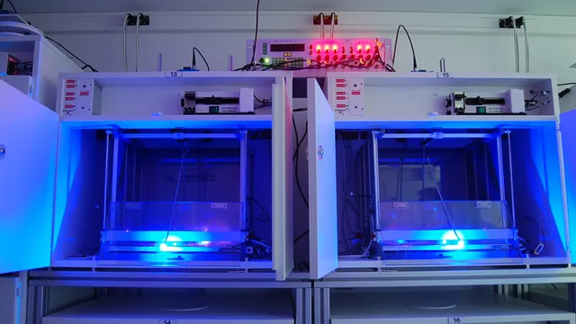 Caixas de laboratório iluminadas por luz azul, com cabos e equipamento eletrónico por cima