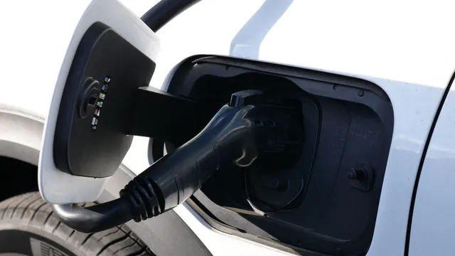 Ficha de carregamento ligada à tomada de um carro elétrico branco, vista de perto