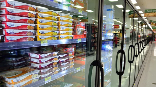 Corredor de congelados de um supermercado, com portas de vidro e prateleiras cheias de refeições embaladas