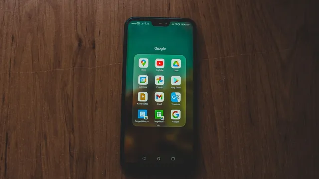 Telemóvel pousado numa mesa de madeira com uma pasta de aplicações da Google aberta no ecrã