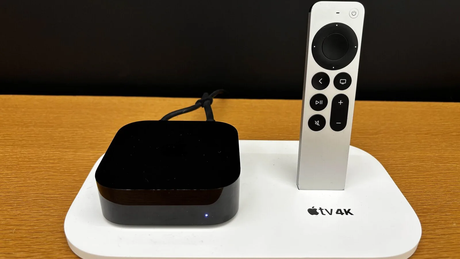 Apple TV 4K preta e comando Siri Remote num expositor branco