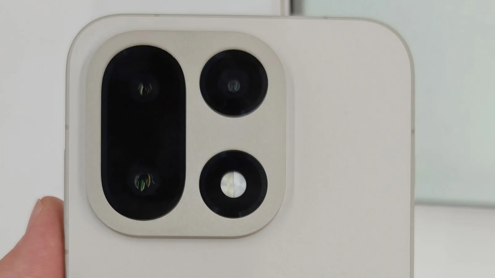Traseira de um OnePlus 15 de cor clara, vista de perto, com o módulo quadrado das três câmaras e o flash